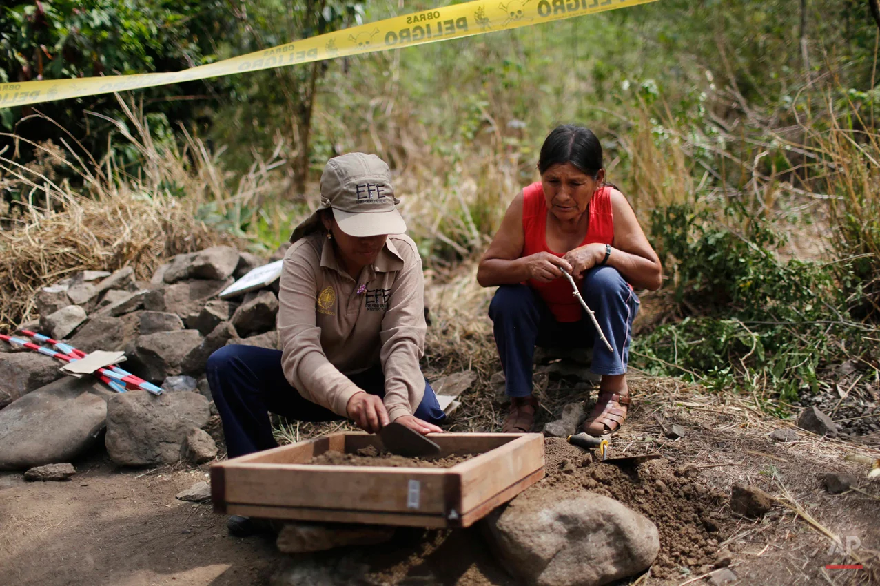 In this Sept. 4, 2014 photo, Severina Osco observes how forensic photographer Angela Inostroza looks for bone fragments in the soil removed in an exhumation of mass graves of villagers slain by security forces in 1984, in the Paccha village of Peru. Osco is trying to locate the body of her sister, Natilda, who disappeared in 1984. (AP Photo/Rodrigo Abd)