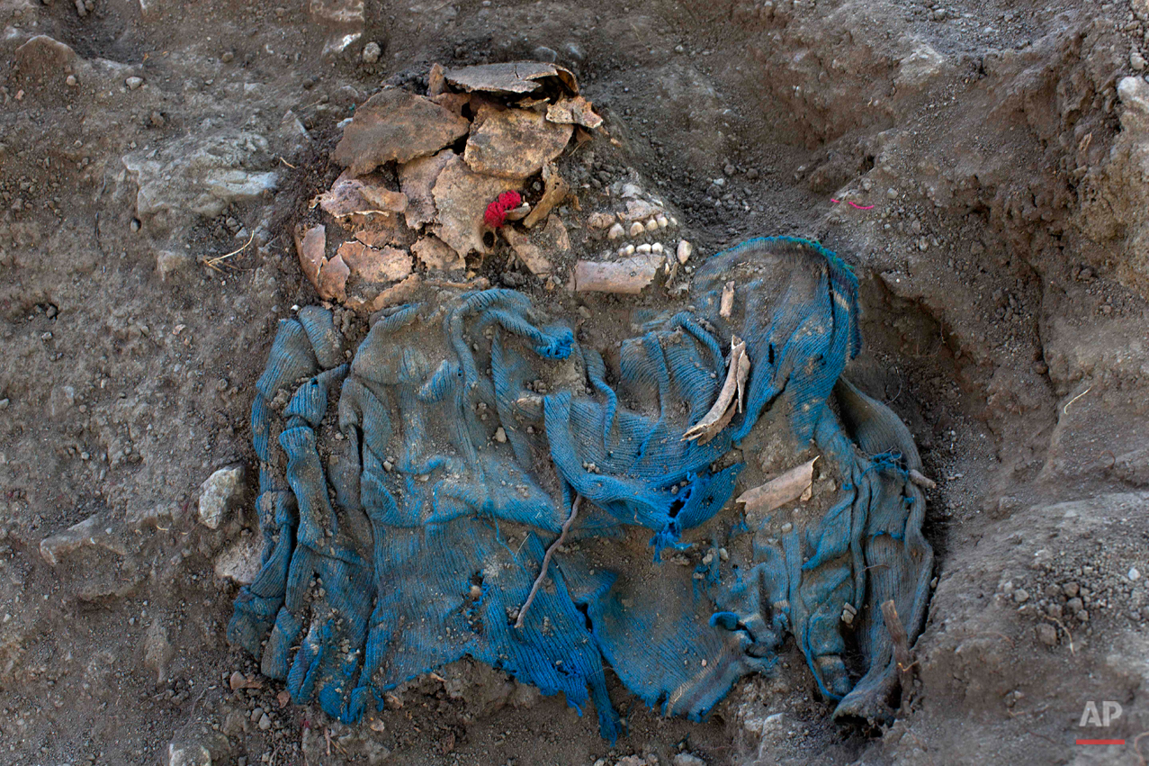  In this Sept. 7, 2014 photo, the remains of an unidentified villager lies unearthed from a common grave, exhumed by forensic anthropologists in the Paccha village of Peru. Forensic investigators began unearthing the remains of the nearly two dozen v
