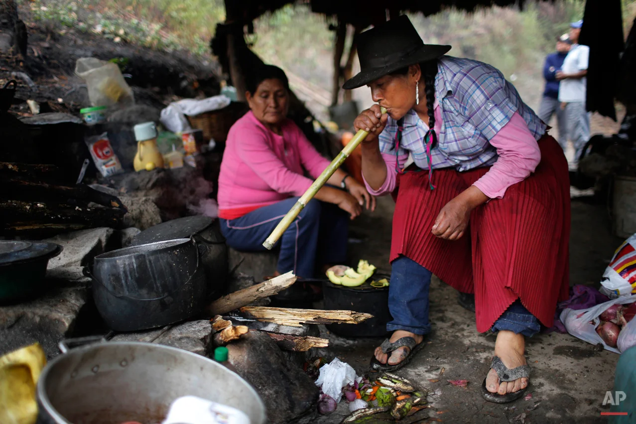 In this Sept. 5, 2014 photo, Dolores Guzman blows into a cane reed to stoke a fire at a makeshift camp in the Paccha village of Peru. Guzman, sole survivor of the Paccha massacre, journeyed from Lima to help forensic investigators find the common graves of the people slain by government security forces in 1984. Before the massacre, the hamlet was a refuge for dozens of families trying to flee the conflict, said Guzman, who was 20 years old and four months pregnant at the time. (AP Photo/Rodrigo Abd)