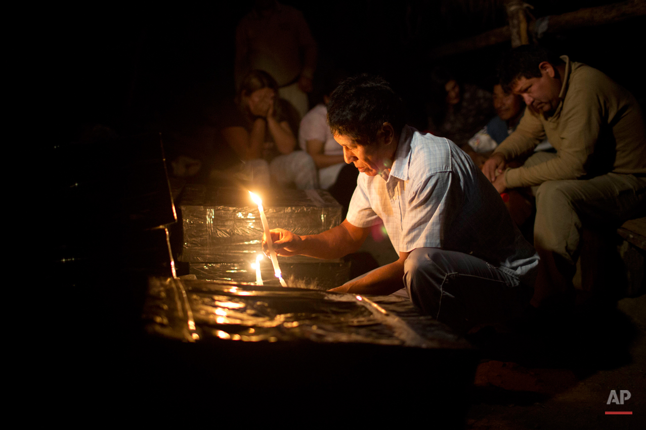  In this Sept. 8, 2014 photo, Cipriano Huaman, who recognized his brother's clothes in an unearthed mass grave, lights a candle during a vigil for remains exhumed by forensic anthropologists in the Peruvian village of Paccha. Forensic investigators b