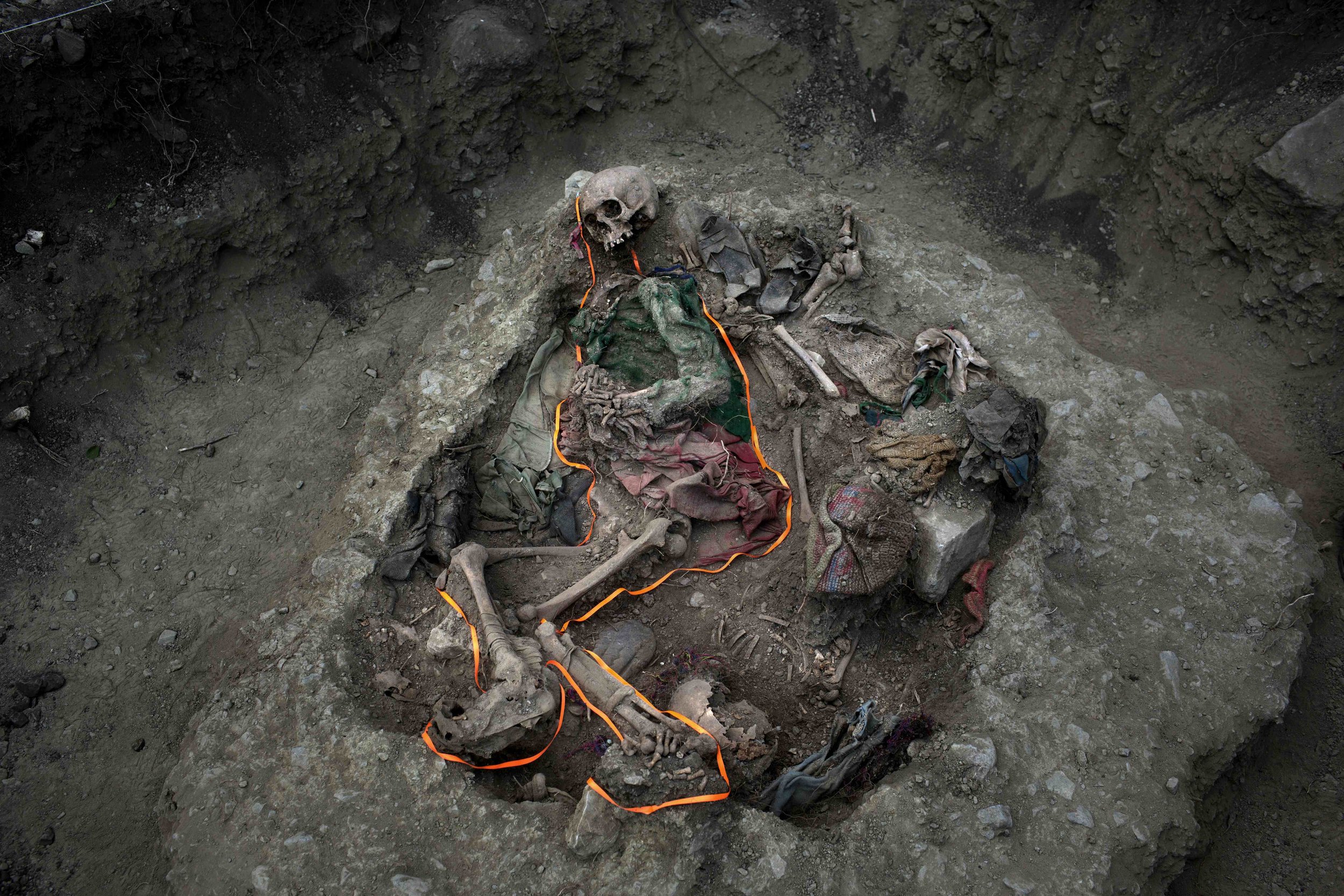  In this Sept. 8, 2014 photo, an orange ribbon outlines skeletal remains in a mass grave, unearthed in the village Paccha of Peru. For three decades, the soil of this unpopulated hamlet on the Andean slopes beside the Apurimac river guarded bodies of
