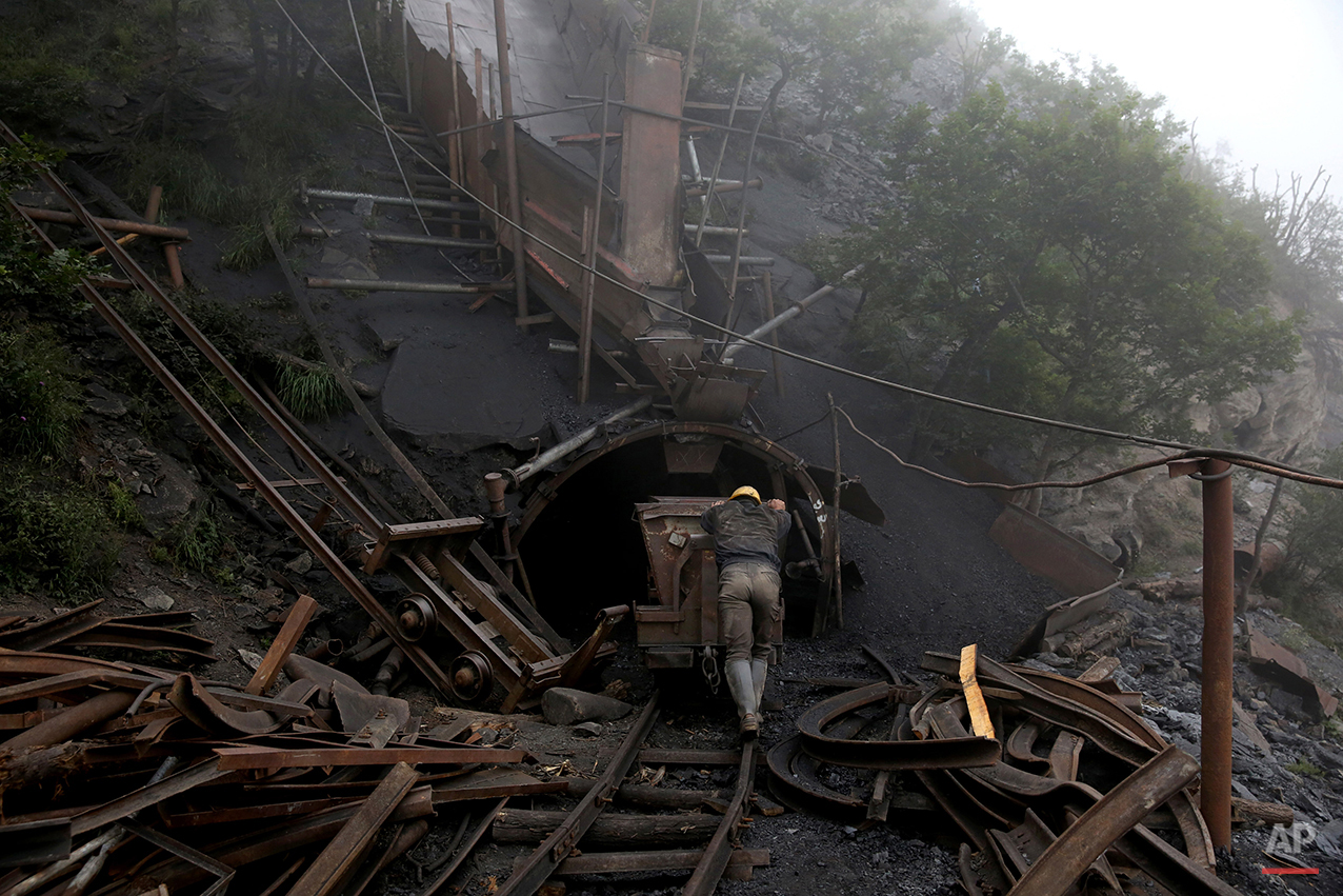  In this Thursday, May 8, 2014 photo, an Iranian coal miner pushes an old metal cart to be loaded with coal at a mine near the city of Zirab 212 kilometers (132 miles) northeast of the capital Tehran on a mountain in Mazandaran province, Iran. A mine