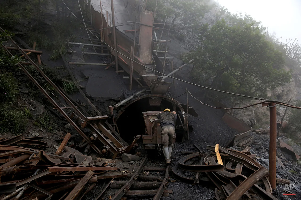 In this Thursday, May 8, 2014 photo, an Iranian coal miner pushes an old metal cart to be loaded with coal at a mine near the city of Zirab 212 kilometers (132 miles) northeast of the capital Tehran on a mountain in Mazandaran province, Iran. A miner said they move up to 100 tons a day. (AP Photo/Ebrahim Noroozi)