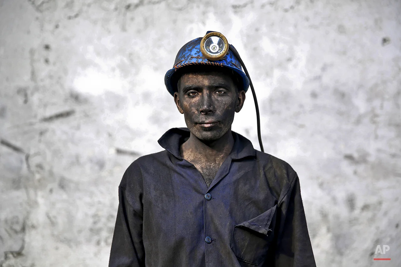 In this Wednesday, May 7, 2014 photo, an Iranian coal miner with his face smeared black from coal poses for a photograph at a mine near the city of Zirab 212 kilometers (132 miles) northeast of the capital Tehran, on a mountain in Mazandaran province, Iran. The workers who put in long hours in often dangerous conditions and make just $300 a month, little more than minimum wage. (AP Photo/Ebrahim Noroozi)