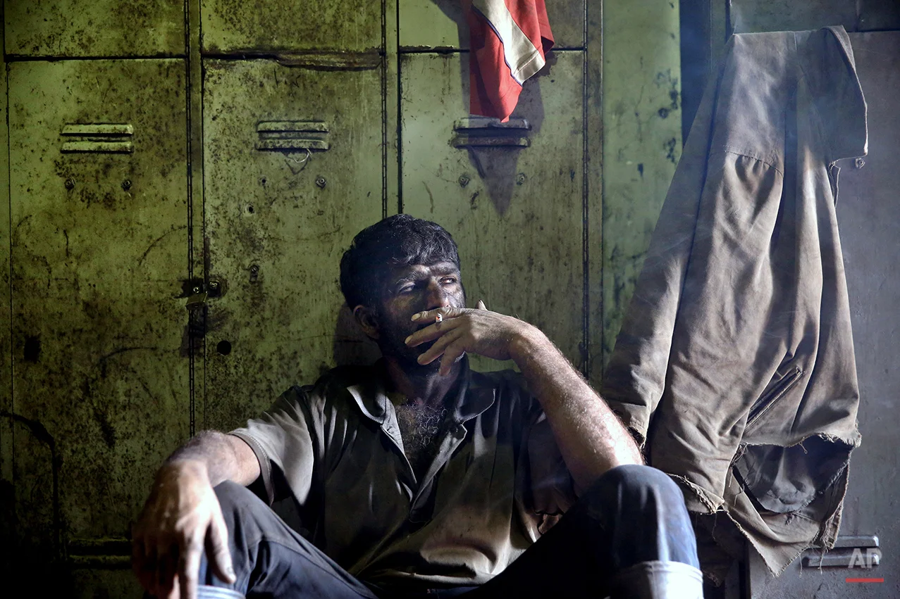 In this Tuesday, Aug. 19, 2014 photo, an Iranian coal miner smokes a cigarette during a break at a mine on a mountain in Mazandaran province, near the city of Zirab 212 kilometers (132 miles) northeast of the capital Tehran, Iran. International sanctions linked to the decade-long dispute over Iran’s nuclear program have hindered the import of heavy machinery and modern technology in all sectors, and coal mining is no exception. The decision to privatize the industry 10 years ago has further squeezed miners, who work often in dangerous conditions -- and make just $300 a month. (AP Photo/Ebrahim Noroozi)