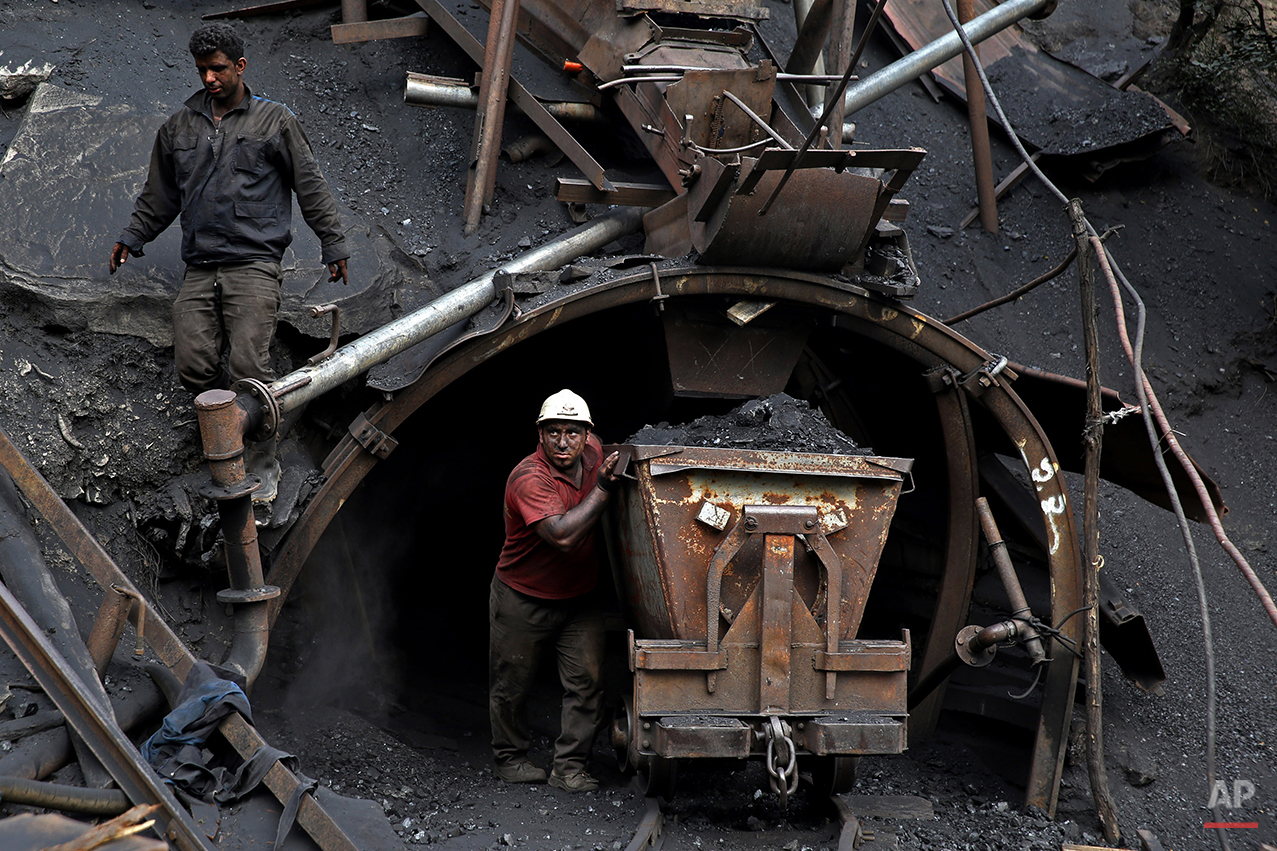  In this Monday, Aug. 18, 2014 photo, an Iranian coal miner pushes a metal cart loaded with coal at a mine near the city of Zirab 212 kilometers (132 miles) northeast of the capital Tehran, on a mountain in Mazandaran province, Iran. The miner move u