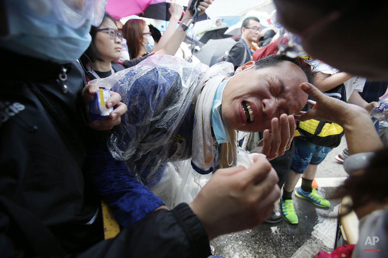  A student protester is overcome by pepper spray from riot police as thousands of protesters surround the government headquarters in Hong Kong Sunday, Sept. 28, 2014. Hong Kong police used tear gas on Sunday and warned of further measures as they tri