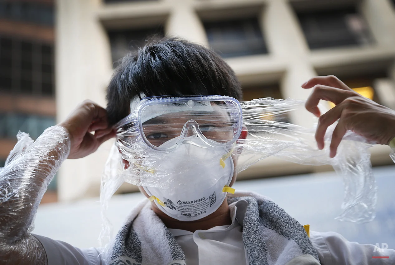 A student pro-democracy protester covers his face in plastic wrap to protect against pepper spray in the event that it is used as they stand-off with local police, Monday, Sept. 29, 2014 in Hong Kong. Pro-democracy protesters expanded their rallies throughout Hong Kong on Monday, defying calls to disperse in a major pushback against Beijing's decision to limit democratic reforms in the Asian financial hub. (AP Photo/Wong Maye-E)