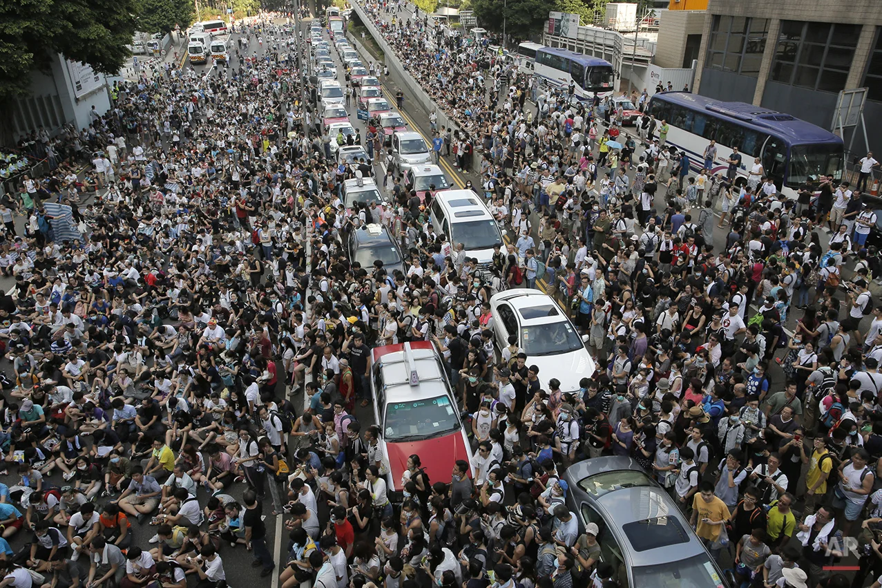 Thousands of people block a main road in Hong Kong, Sunday, Sept. 28, 2014. Hong Kong activists kicked off a long-threatened mass civil disobedience protest Sunday to challenge Beijing over restrictions on voting reforms, escalating the battle for democracy in the former British colony after police arrested dozens of student demonstrators. (AP Photo/Vincent Yu)