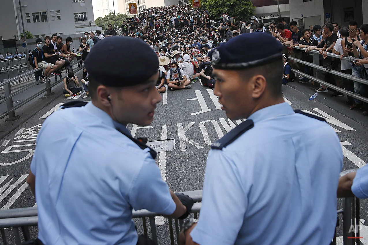 Pro-democracy protesters sit on a road as they face-off with local police, Monday, Sept. 29, 2014 in Hong Kong. Pro-democracy protesters expanded their rallies throughout Hong Kong on Monday, defying calls to disperse in a major pushback against Beijing's decision to limit democratic reforms in the Asian financial hub. (AP Photo/Wong Maye-E)