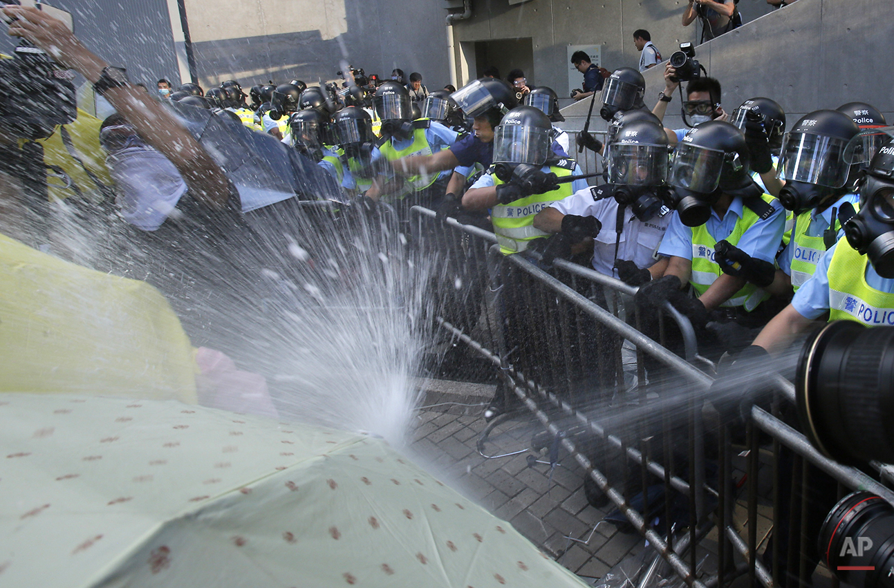 Riot police fire pepper spray on student protesters surrounding the government headquarters in Hong Kong, Sunday, Sept. 28, 2014. Hong Kong police used tear gas on Sunday and warned of further measures as they tried to clear thousands of pro-democra