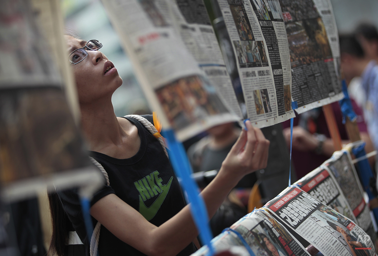  A woman reads the latest newspaper articles displayed at a sit-in protest in Hong Kong, Monday, Sept. 29, 2014. Pro-democracy protesters expanded their rallies throughout Hong Kong on Monday, defying calls to disperse in a major pushback against Bei