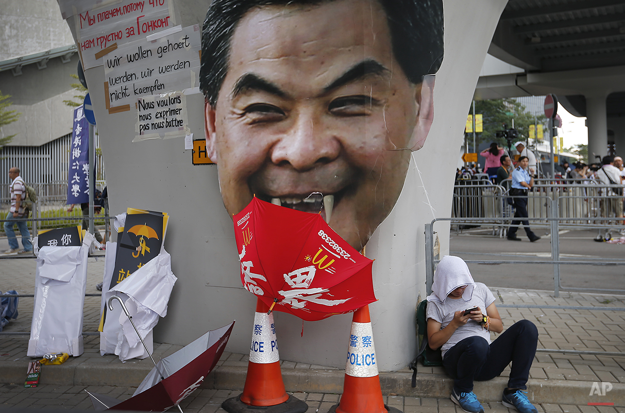  A student protester rests next to a defaced cut-out of Hong Kong's Chief Executive Leung Chun-ying at one of their protest sites around the government headquarters, Tuesday, Sept. 30, 2014, in Hong Kong. Pro-democracy protesters in Hong Kong set a W