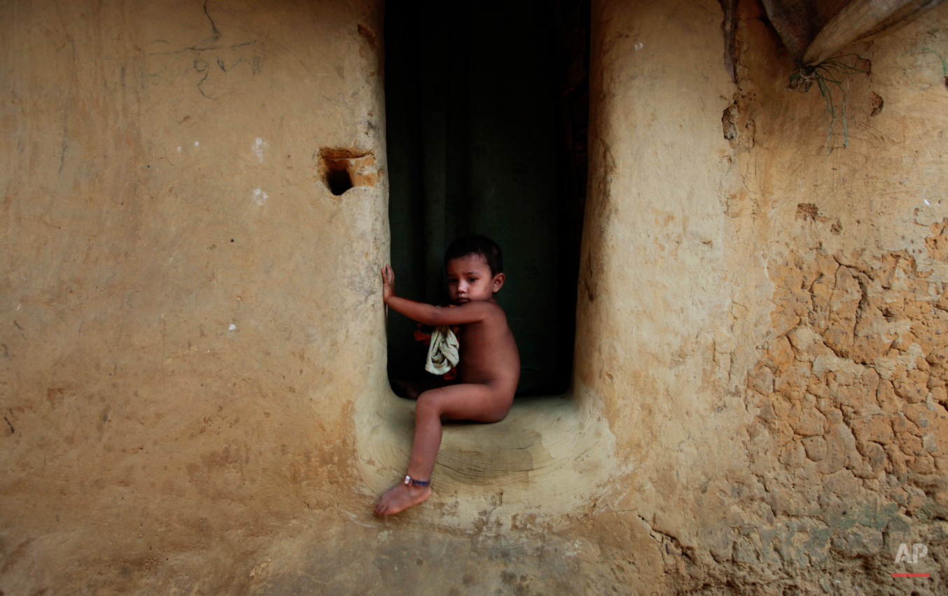  A young Rohingya Muslim boy sits at the entrance to his home at an unauthorized camp that houses Rohingya Muslim refugees who fled Myanmar during an ethnic strife in 1992, in Kutupalong, Bangladesh on World Refugee Day, Wednesday, June 20, 2012. Wor