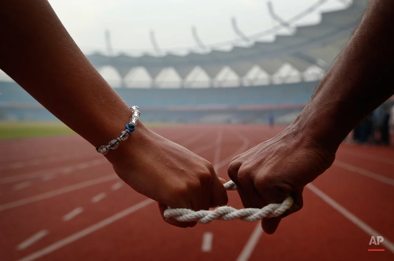 In this Tuesday, Dec. 11, 2012 photo, a blind athlete, left, is connected to her guide as she gets ready to run during the 18th National Sports Meet for the Blind in New Delhi, India. The four day event ends Friday. (AP Photo/Saurabh Das)