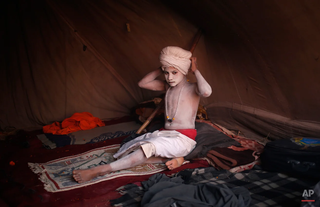 A newly initiated Hindu monk of the Shri Panchayati Naya Udasin "akhara" or sect, puts on a turban during the Maha Kumbh festival in Allahabad, India, Tuesday, Jan. 29, 2013. Millions of Hindu pilgrims are expected to attend the Maha Kumbh festival, which is one of the world's largest religious gatherings that lasts 55 days and falls every 12 years. During the festival pilgrims bathe in the holy Ganges River in a ritual they believe can wash away their sins. (AP Photo/Saurabh Das)