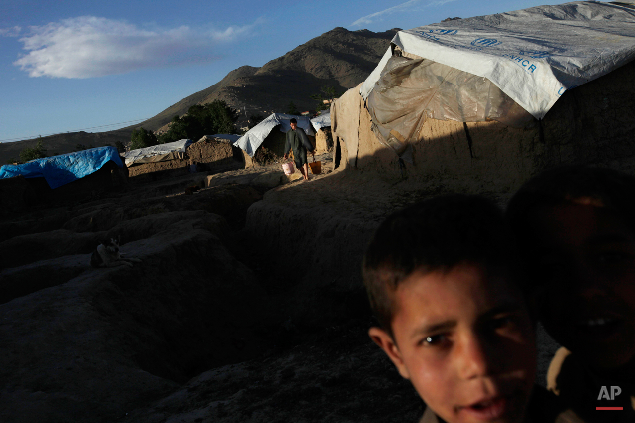  An internally displaced man carries water to his hut as a small boy looks on at a camp for the internally displaced in Kabul, Afghanistan, Thursday, May 13, 2010. (AP Photo/Saurabh Das) 