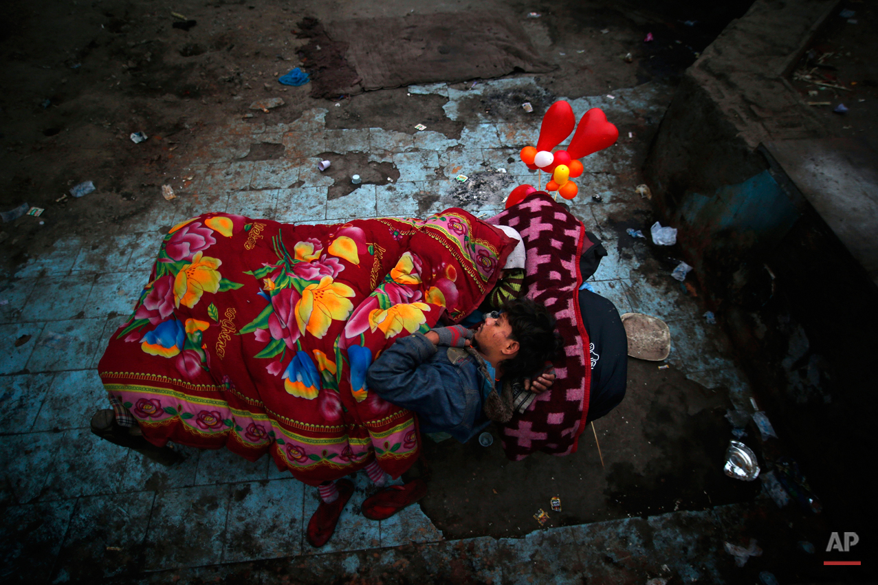  A homeless man and his wife, white scarf covering her head, share a rented bed as balloons inflated in the shape of hearts adorn their cot at a poor neighborhood in New Delhi, India, Wednesday, Jan. 15, 2014. Beds on a cot with blankets cost approxi