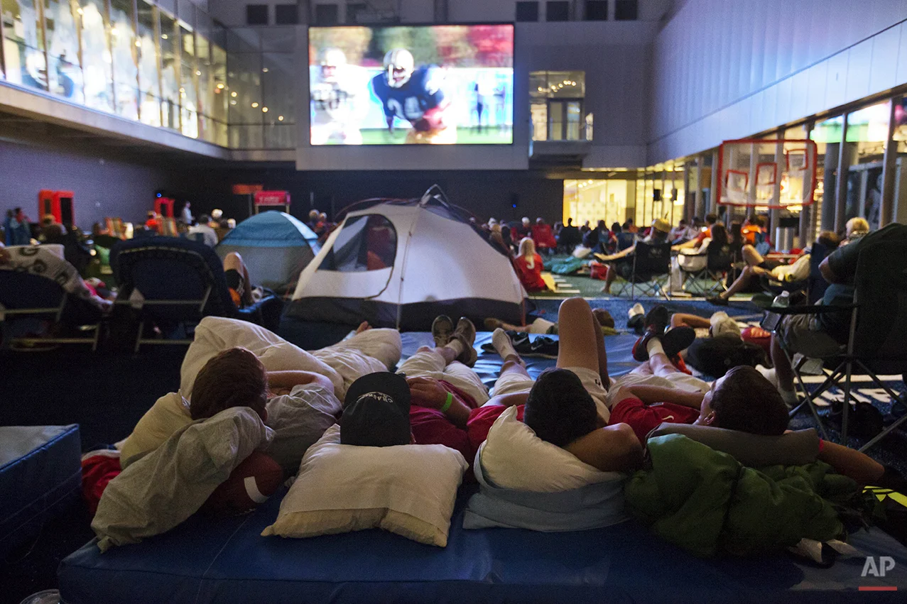 From left, Danny Mason, Walker Tuten, Nick Toomey and Matt Filer, watch the movie "Rudy" during a sleepover in the College Football Hall of Fame, Wednesday, Aug. 13, 2014, in Atlanta. The crowd fell asleep to the playing of college football themed movies such as "Rudy" and "We are Marshall" on the jumbotron. (AP Photo/David Goldman)