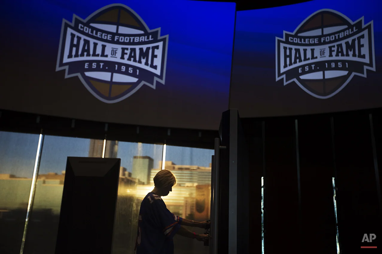Valerie Herriman, of Augusta, Ga., tours the College Football Hall of Fame before spending the night there as the sun sets against the downtown skyline in the background, Wednesday, Aug. 13, 2014, in Atlanta. One hundred contest winners who wrote an essay detailing their love of college football were selected to stay with a guest overnight in Atlanta’s College Football Hall of Fame before its grand opening and win a year’s supply of Chick-fil-A. (AP Photo/David Goldman)