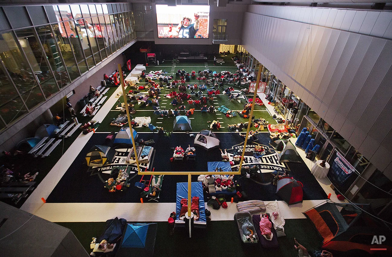 Guests watch from the turf as the movie "Rudy" is plays during a sleepover in the College Football Hall of Fame in the early hours, Thursday, Aug. 14, 2014, in Atlanta. The crowd of 200 who came from as far away as Hawaii were among the first to experience the College Football Hall of Fame and Chick-fil-A Fan experience before it opened to the public on Aug. 23. (AP Photo/David Goldman)