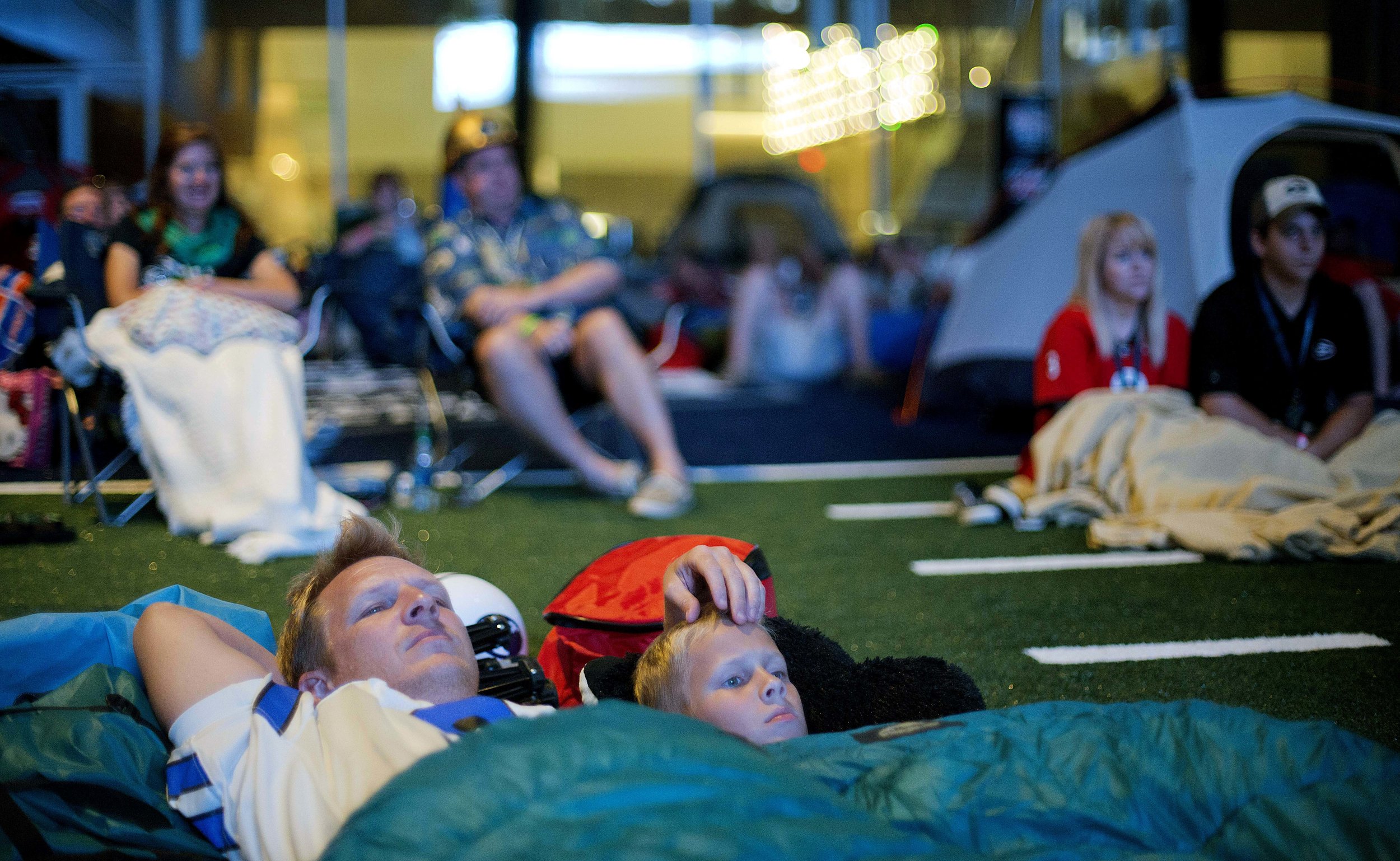  Chip Kent and his son C.J., 9, of Suwanee, Ga., watch from their sleeping bags as the movie "Rudy" is played during a sleepover in the College Football Hall of Fame just after midnight, Thursday, Aug. 14, 2014, in Atlanta. One hundred contest winner