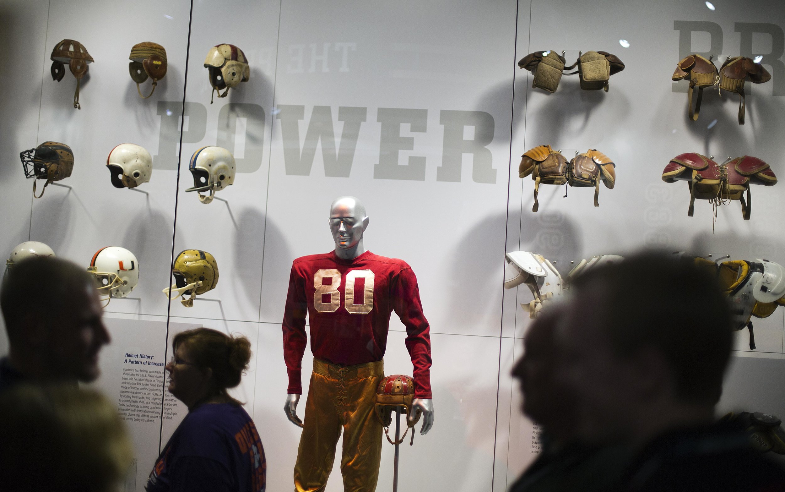  An exhibit displaying the evolution of protective equipment is viewed by visitors during a tour at the College Football Hall of Fame, Wednesday, Aug. 13, 2014, in Atlanta. One hundred contest winners who wrote an essay detailing their love of colleg