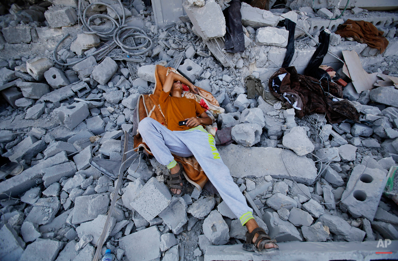  A Palestinian sleeps on the rubble of his home in Beit Hanoun, Gaza Strip, Monday, Aug. 11, 2014. An Egyptian-brokered cease-fire halting the Gaza war held into Monday morning, allowing Palestinians to leave homes and shelters as negotiators agreed 