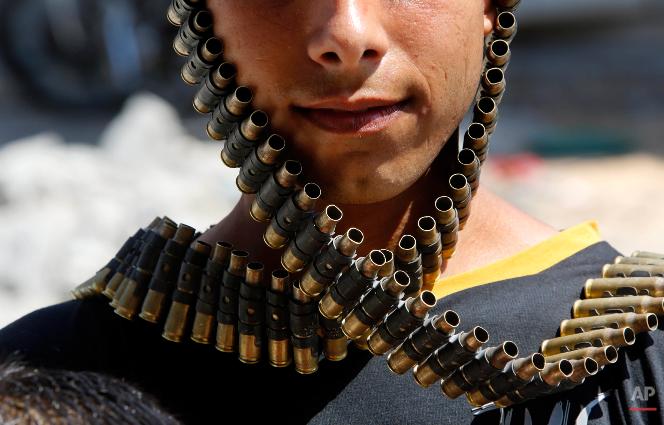  A Palestinian youth wraps a bandolier of spent bullets leftover by the Israeli army, next to his destroyed home in Beit Hanoun, Gaza Strip, Monday, Aug. 11, 2014. An Egyptian-brokered cease-fire halting the Gaza war held into Monday morning, allowin