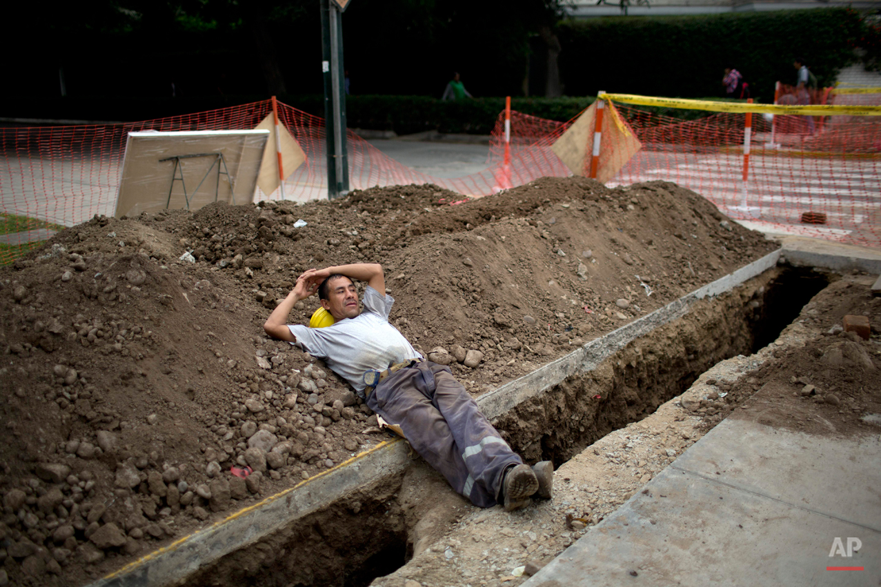  German Palencia rests on a pile of dirt after digging ditches for a telecommunications company in Lima Peru, Friday, June 6, 2014.  (AP Photo/Rodrigo Abd) 