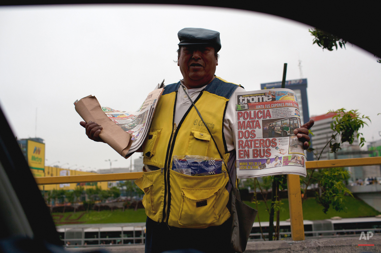  A newspaper vendor shows the cover of a newspaper with the headline in Spanish "Police kill two petty thieves inside a bus" in Lima, Peru, Monday, Nov. 5, 2012. (AP Photo/Rodrigo Abd) 