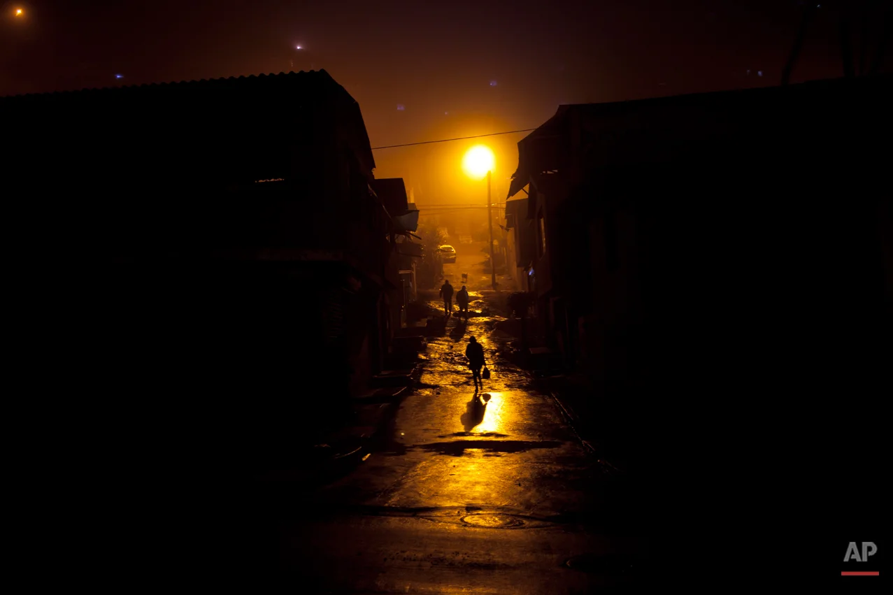 People walk through a mud street in Villa Maria del Triunfo district, Lima, Peru, Wednesday, July 24, 2013. (AP Photo/Rodrigo Abd)