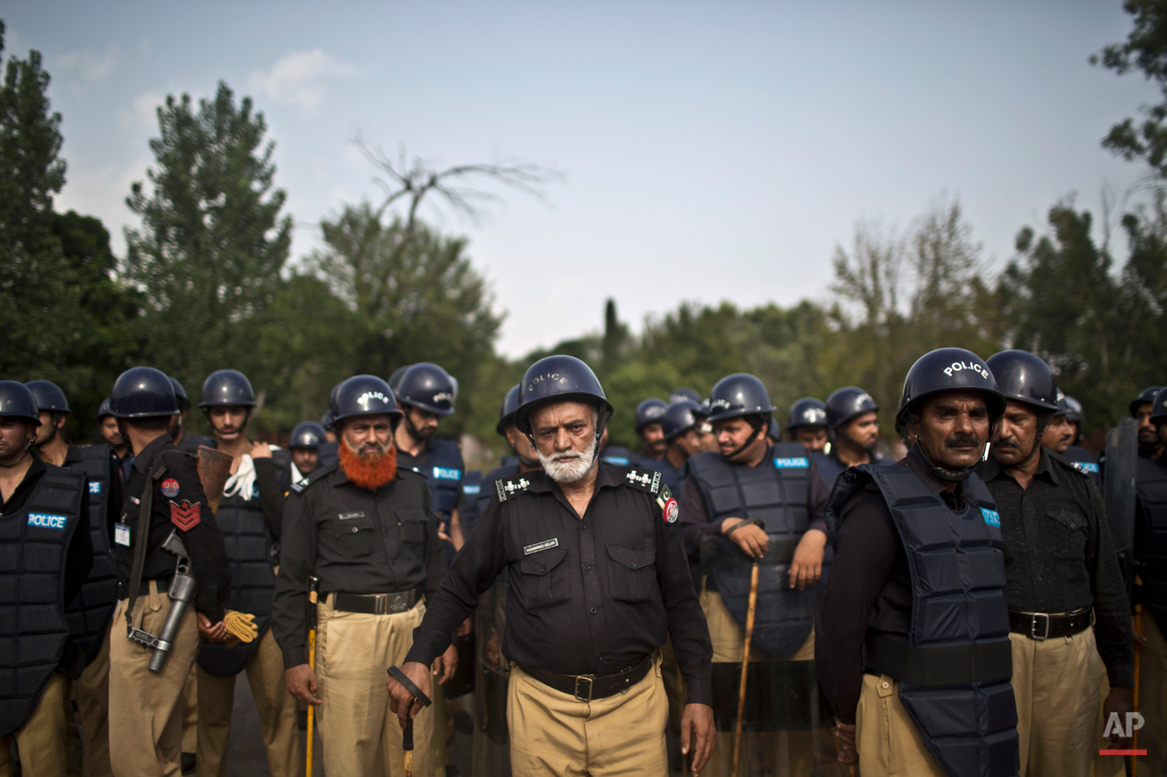 Pakistani police officers stand guard near the Parliament building after tens of thousands of protesters entered Islamabad's high-security Red Zone the night before, five days after arriving in the capital from the eastern city of Lahore in convoys, in Islamabad, Pakistan, Wednesday, Aug. 20, 2014. Pakistani lawmakers met Wednesday as tens of thousands of protesters thronged outside the assembly calling for the resignation of Prime Minister Nawaz Sharif over alleged voting fraud. (AP Photo/Muhammed Muheisen)