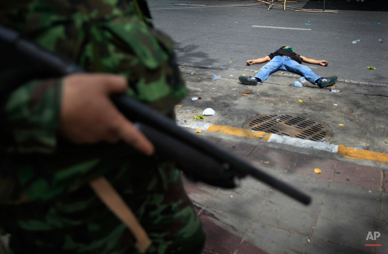  Thai soldiers storm into anti-government protesters' encampment while a protester lies dead on Wednesday May 19, 2010, in Bangkok, Thailand. Downtown Bangkok became a raging battleground Wednesday as the army stormed a barricaded protest camp and th