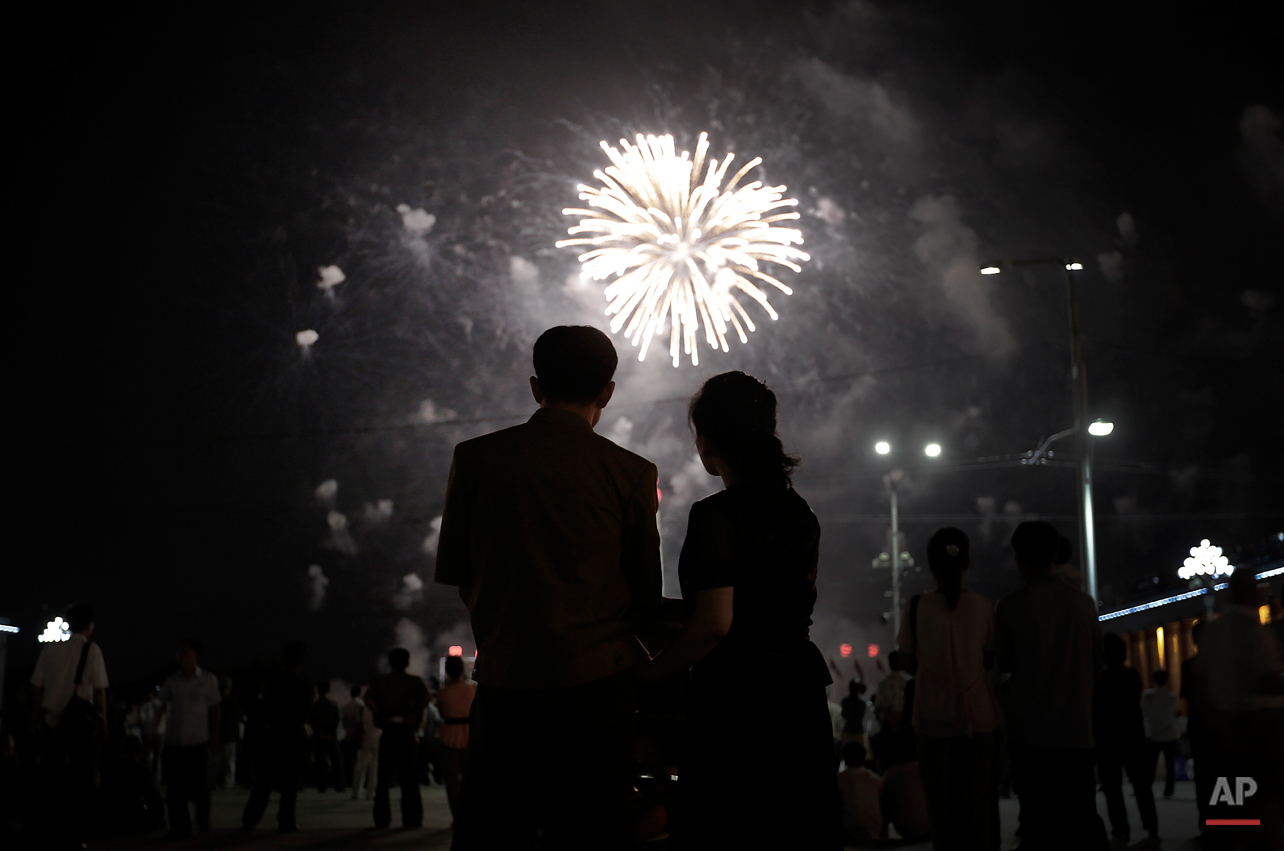  A North Korean couple is silhouetted against a fireworks explosion, Sunday, July 27, 2014 in central Pyongyang, North Korea. North Koreans gathered at Kim Il Sung Square to watch a fireworks display as part of celebrations for the 61st anniversary o