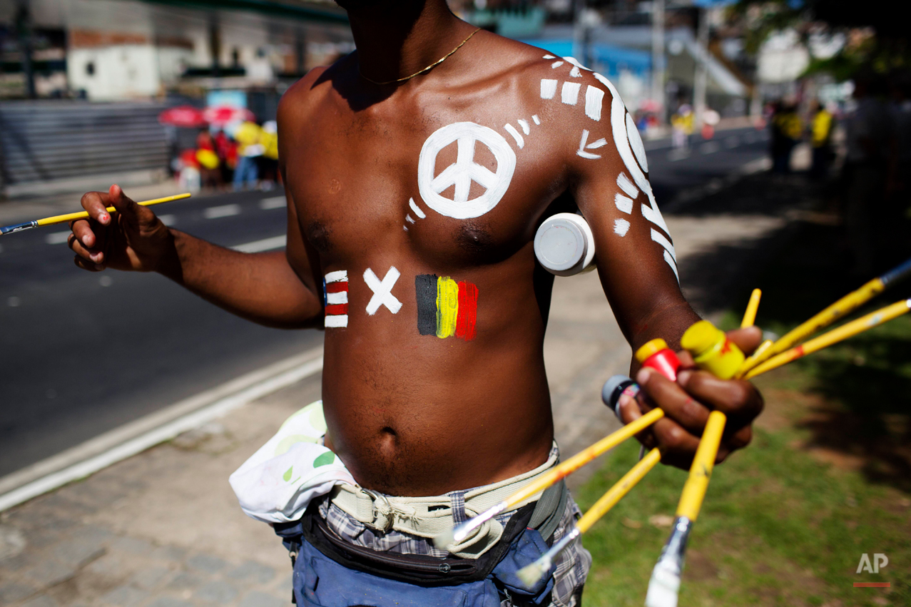  A body painter with the U.S. and Belgian flags painted on his body waits for customers before World Cup round of 16 match between the U.S. and Belgium, outside the Arena Fonte Nova stadium in Salvador, Brazil, Tuesday, July 1, 2014. (AP Photo/Rodrig