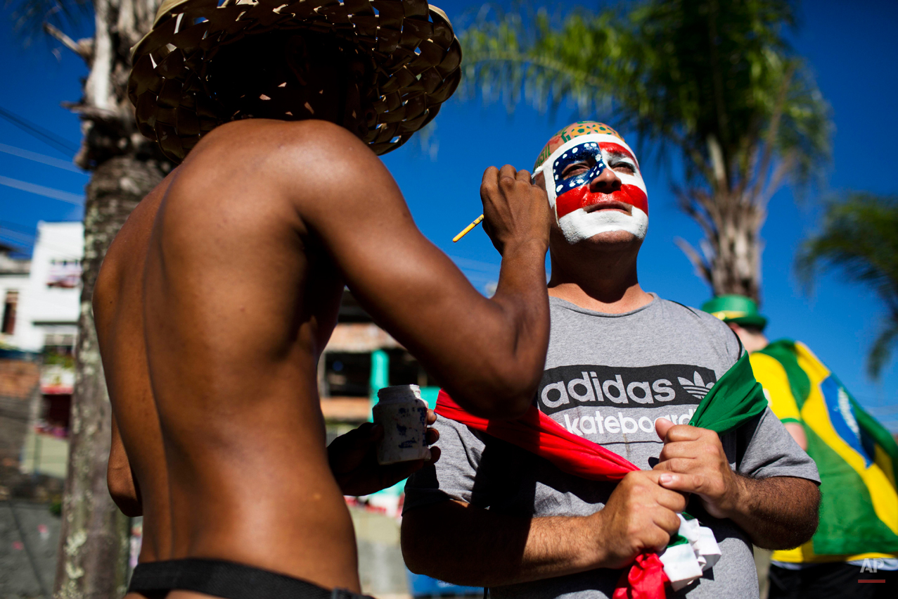  A man paints the United States colors on a soccer fan's face before a World Cup round of 16 match between the U.S. and Belgium outside the Arena Fonte Nova stadium in Salvador, Brazil, Tuesday, July 1, 2014. (AP Photo/Rodrigo Abd) 