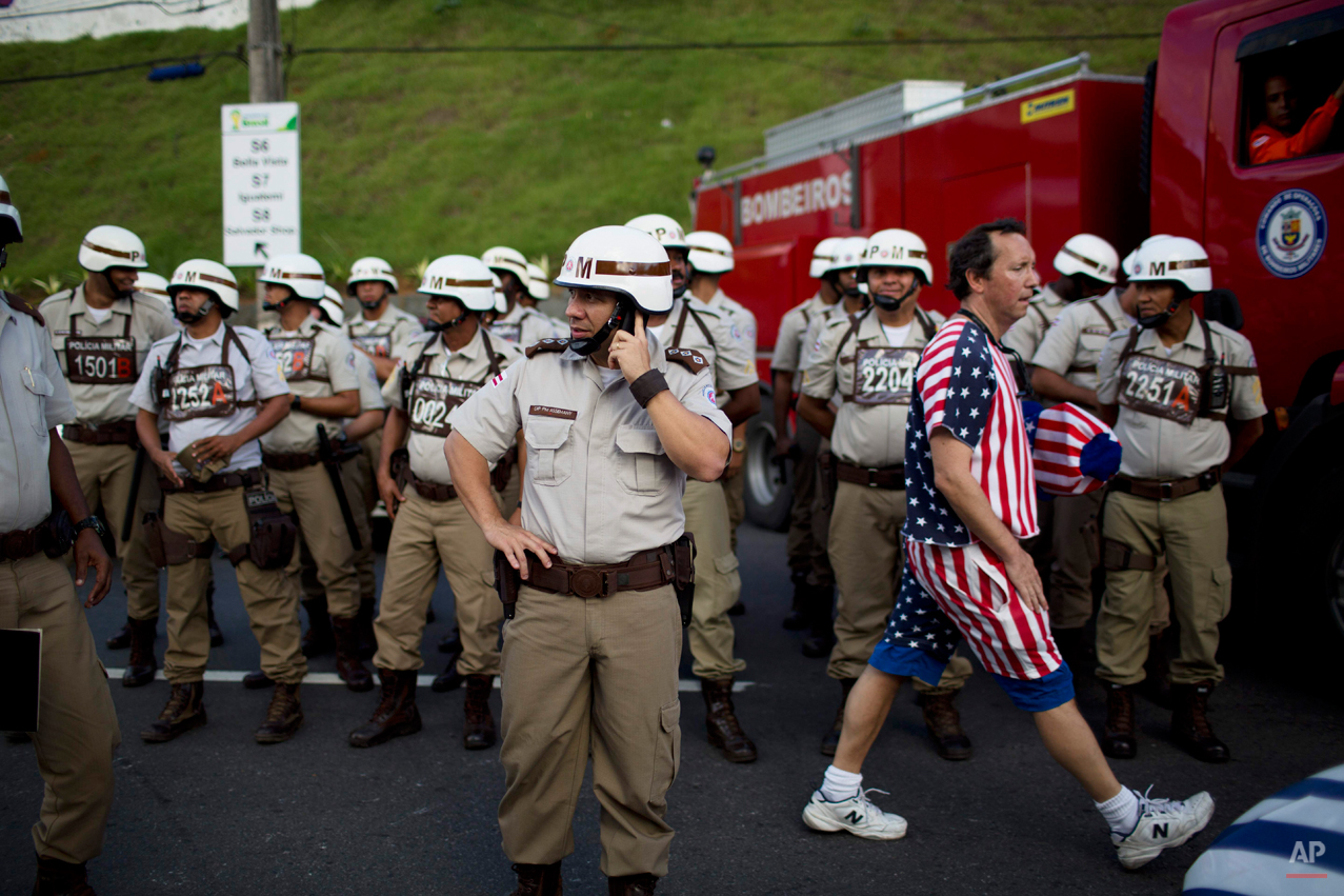  A soccer fan of the U.S. walks amid military policemen standing guard outside the Arena Fonte Nova stadium before World Cup round of 16 match between the U.S. and Belgium in Salvador, Brazil, Tuesday, July 1, 2014. (AP Photo/Rodrigo Abd) 