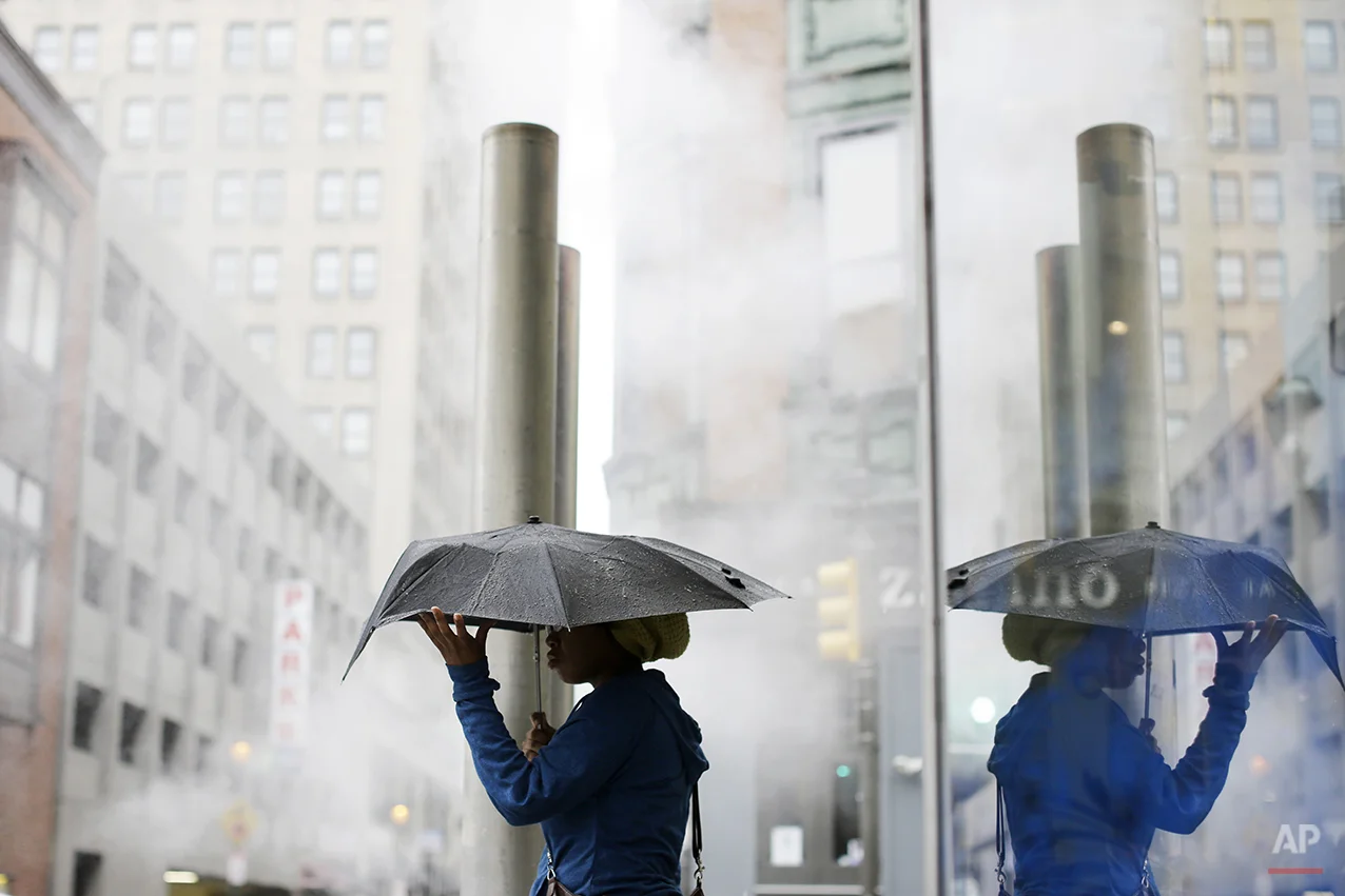 A woman shields herself with an umbrella during an afternoon rainstorm Friday, Oct. 11, 2013, in Philadelphia. The exhibition is scheduled to run through Jan. 5, 2014. (AP Photo/Matt Rourke)