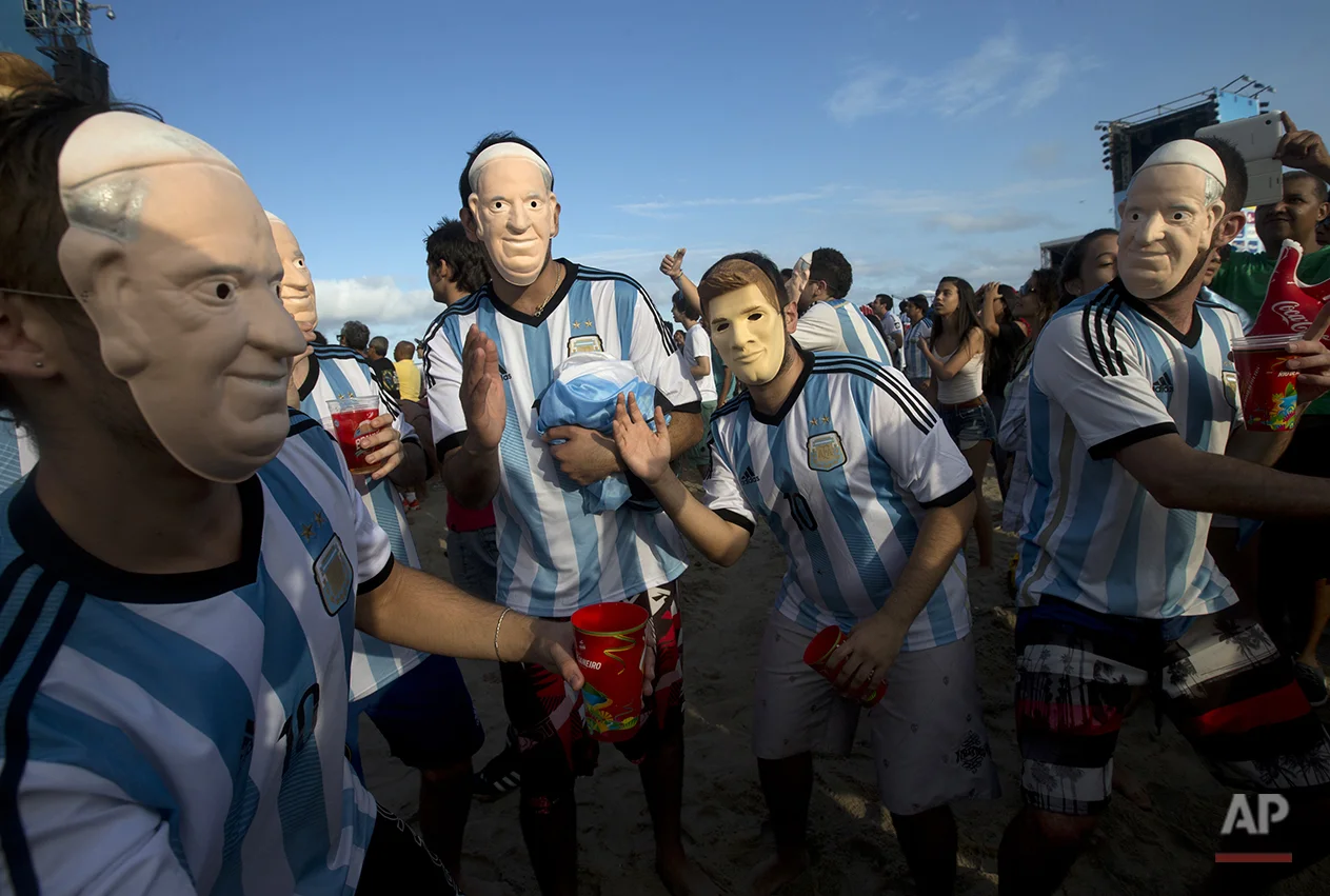 Argentina soccer fans wear masks in the likeness of Pope Francis and Argentina's player Lionel Messi as they attend a live telecast of the World Cup semifinal match between Argentina and Netherlands, inside the FIFA Fan Fest area on Copacabana beach in Rio de Janeiro, Brazil, Wednesday, July 9, 2014. (AP Photo/Silvia Izquierdo)