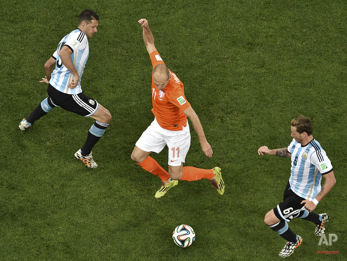  Netherlands' Arjen Robben, center, controls the ball between Argentina's Martin Demichelis, left, and Lucas Bigli, right, during the World Cup semifinal soccer match between the Netherlands and Argentina at the Itaquerao Stadium in Sao Paulo, Brazil