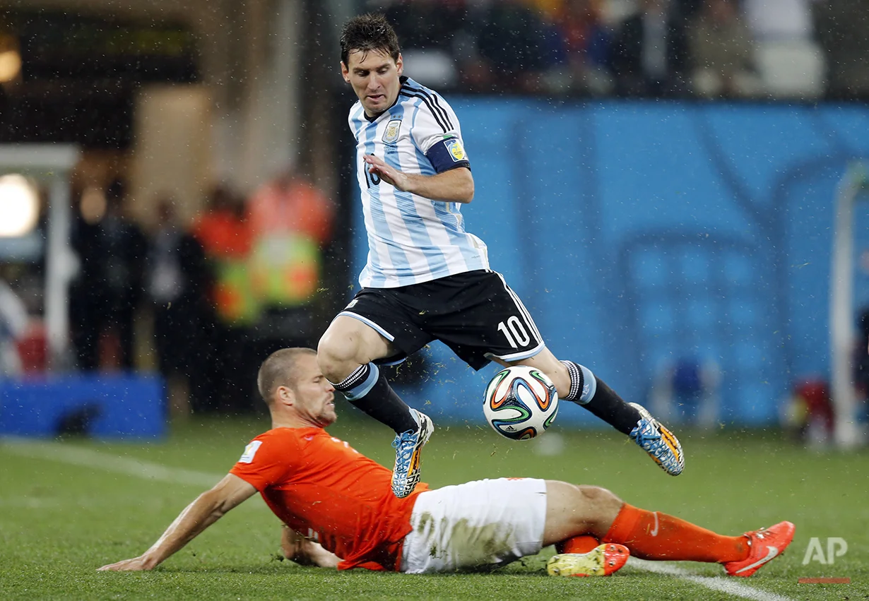 Netherlands' Ron Vlaar, bottom, tackles Argentina's Lionel Messi during the World Cup semifinal soccer match between the Netherlands and Argentina at the Itaquerao Stadium in Sao Paulo, Brazil, Wednesday, July 9, 2014. (AP Photo/Frank Augstein)