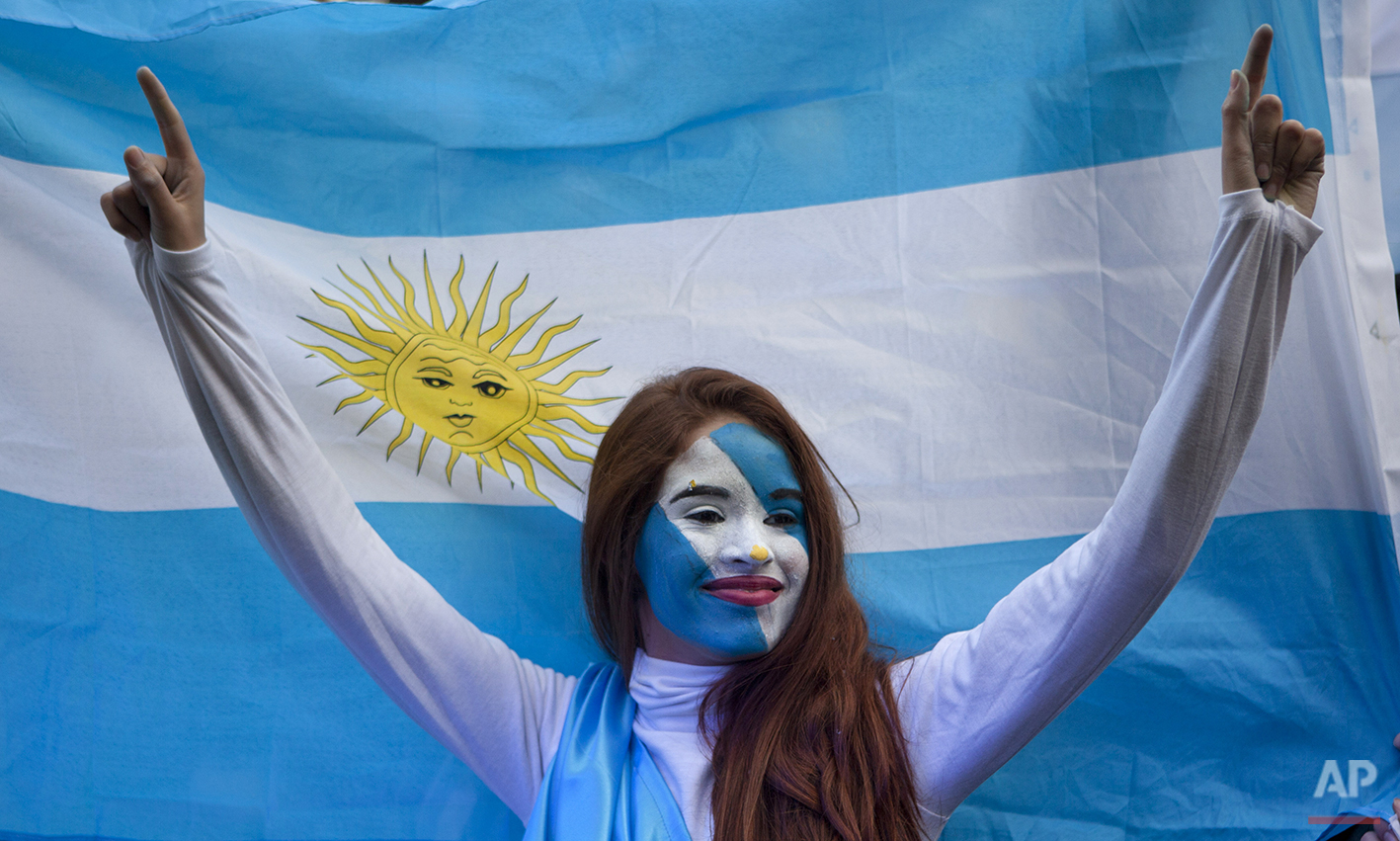  An Argentina soccer fan poses in front of an Argentine flag before a World Cup semifinal match between Argentina against Netherlands, on a street where an outdoor screen has been set for viewing, in Buenos Aires, Argentina, Wednesday, July 9, 2014. 