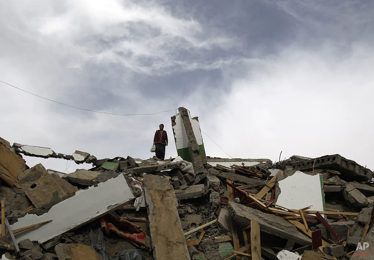 A Tibetan woman stands on top a collapsed building in Yushu County, northwest China's Qinghai province, Friday, April 16 , 2010. Armed with life detectors, rescuers searched for survivors Friday more than 48 hours after an earthquake leveled homes in western China, killing at least 760 people. (AP Photo/Andy Wong)