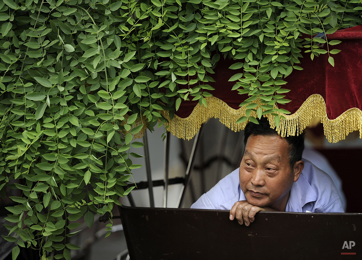  A Chinese man looks out from his trishaw as he waits for customer at a hutong alley near the drum tower in Beijing, China, Wednesday, May 26, 2010. (AP Photo/Andy Wong) 