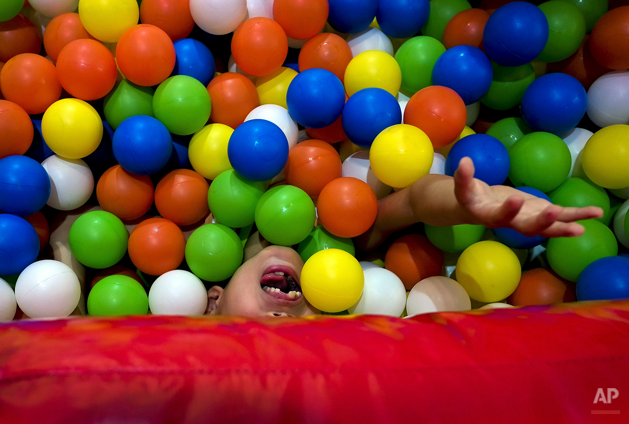  A child plays on an inflatable balloon bouncer fill with balls set up by an exhibitor during the Kids Fun Expo in Beijing, China Thursday, July 25, 2013. (AP Photo/Andy Wong) 