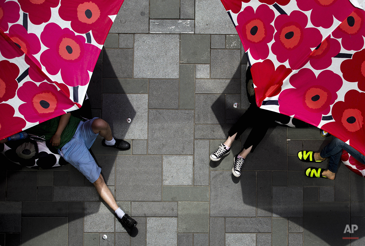  Chinese shoppers take a rest on cushions placed underneath parasols which displayed at a shopping mall as a fashion brand promotion in Beijing Sunday, June 8, 2014. (AP Photo/Andy Wong) 