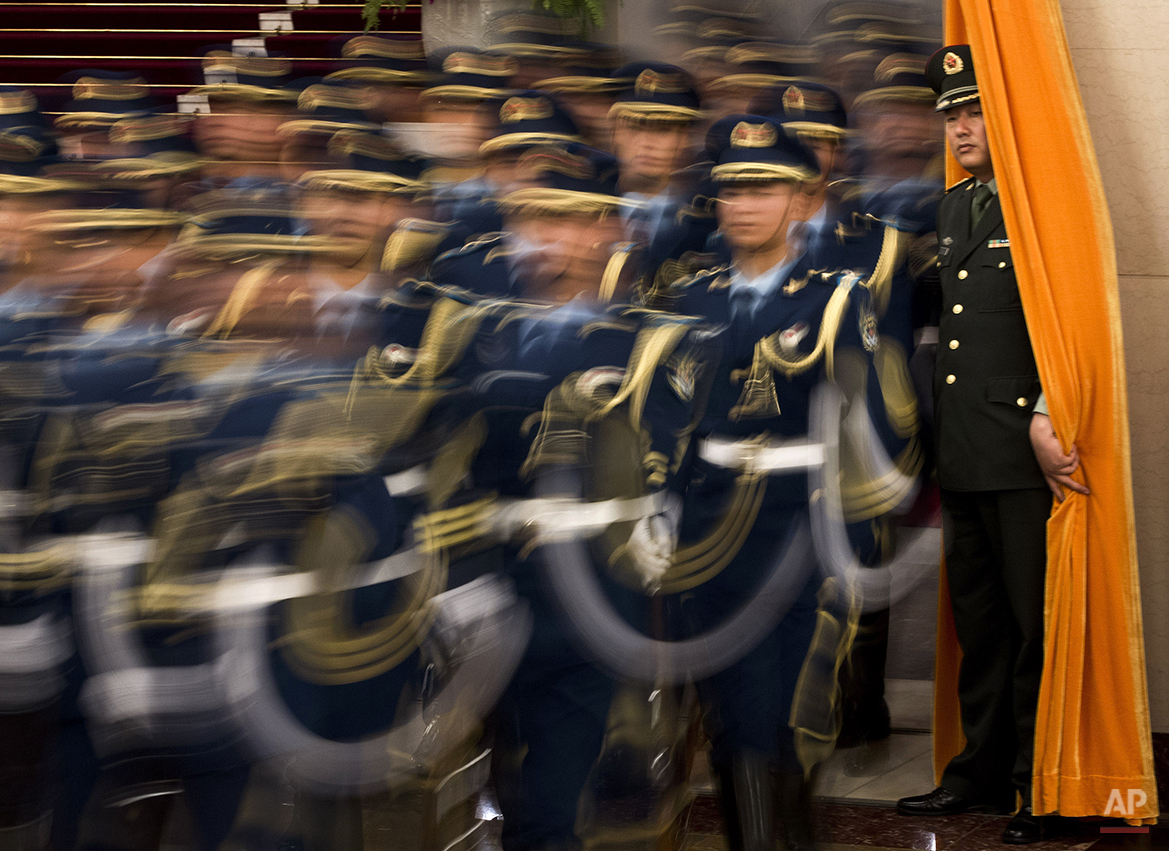  A Chinese military officer watches members of a honor guard march into a hall for a welcome ceremony for Mongolian President Elbegdorj Tsakhia, unseen, at the Great Hall of the People in Beijing Thursday, June 7, 2012. (AP Photo/Andy Wong) 