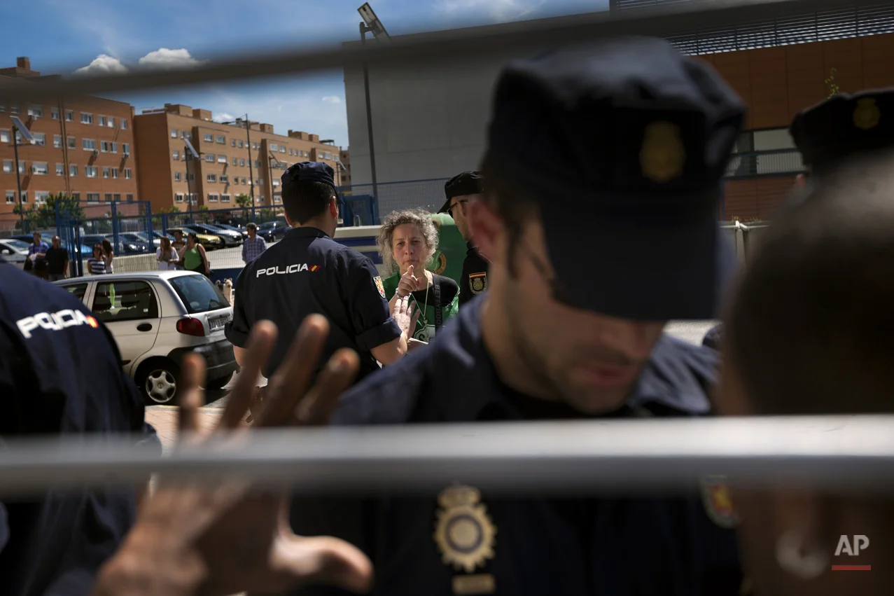 Veronica Carro Cabaninas, 51 years old, born in Argentina and with Spanish citizenship speaks with police officers before her eviction from her house, in Parla, Spain, Wednesday, April 30, 2014. Veronica, a former gardener and concierge at Parla's townhall, has resided in the apartment with her 14 year old daughter Rocio for the past 5 years, but since being unemployed for the last 3 years and her only income was a state handout of 426 euros ($584) a month she could not afford to pay a protected rent of 370 euros a month ($513) to Lazora, a private investor company who bought her house from the City Hall Housing and Land Company (EMVS). Lazora demanded their eviction. (AP Photo/Daniel Ochoa de Olza)