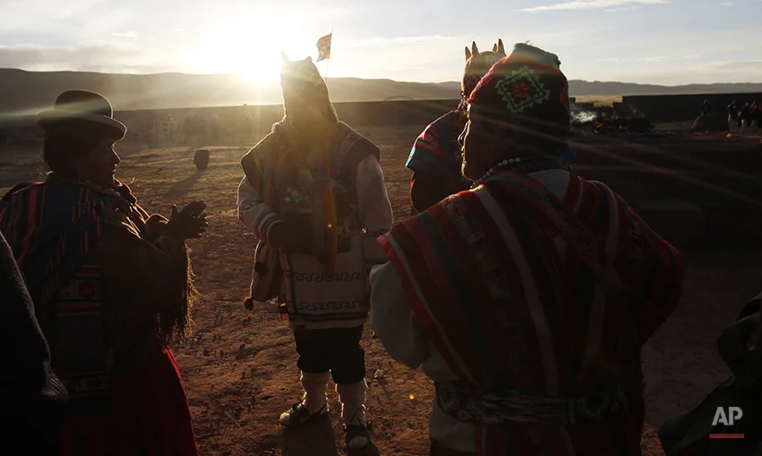 Aymara indigenous men and women attend a new years ritual at the ruins of the ancient civilization of Tiwanaku located in the highlands in Tiwanaku, Bolivia, early Saturday, June 21, 2014. Bolivia's Aymara Indians are celebrating the year 5,522 as well as the Southern Hemisphere's winter solstice, which marks the start of a new agricultural cycle. (AP Photo/Juan Karita)
